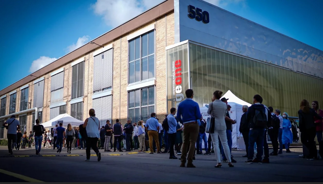 Eingangsbereich auf dem Areal – Besucher:innen vor der Halle
